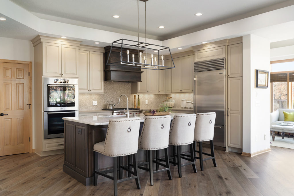 A newly remodeled kitchen with an island accompanied by four chairs.